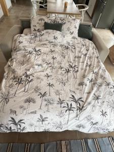 a bed with a black and white blanket with palm trees at Maison entre océan et forêt landaise in Vielle-Saint-Girons