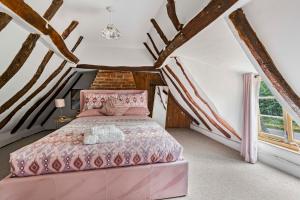 ein Schlafzimmer mit einem rosa Bett im Dachgeschoss in der Unterkunft Two Bedroom Grade ll Cottage At AZ Luxury Stays Honey Horsefield With WiFi And Free Parking in Hundon + 30 Fotos