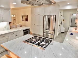 Una cocina con gabinetes blancos y un refrigerador de acero inoxidable. en Beachfront Estate - LB Peninsula, en Long Beach