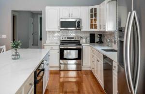 a kitchen with white cabinets and a stainless steel refrigerator at Maplewood Manor - Chic 6 BDR Downtown Walworth in Walworth