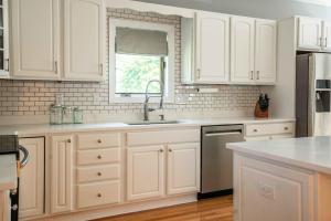 a kitchen with white cabinets and a sink and a window at Maplewood Manor - Chic 6 BDR Downtown Walworth in Walworth +39 photos