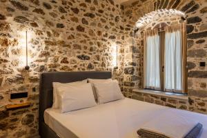 a bedroom with a bed with a stone wall at Alsalos Apartment in Kardamili +37 photos