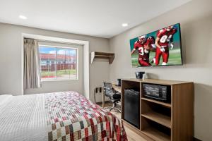 尤利斯Red Roof Inn & Suites Euless - DFW Airport Southwest的一间卧室，墙上有一张床和一台电视