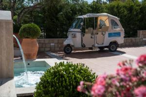 a golf cart is parked next to a fountain at Hotel Baia Del Capitano in Cefalù