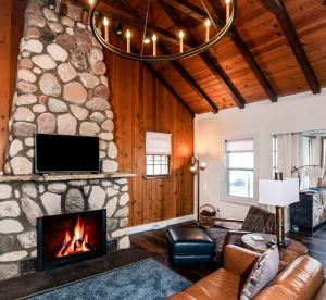 a living room with a stone fireplace and a tv at Como Collection - 2 Homes 2 Lakes 1 Rental in Lake Geneva