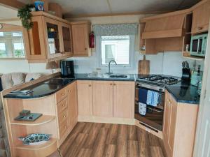 a kitchen with wooden cabinets and a stove top oven at Summer Dreams in Amroth