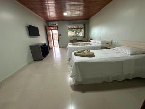 a room with two beds and a television in it at Pousada de Itajuipe in Vitória da Conquista +16 photos
