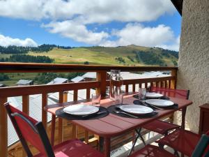 a table on a balcony with a view of the mountains at Appartement chalet en plein centre des Saisies in Hauteluce +16 photos