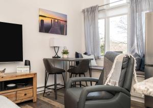 a living room with a table and chairs and a tv at The Hideaway at Hayloft Lodge - Chic & Unique Stay in Lake Geneva