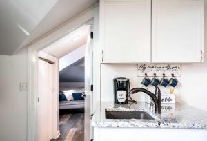 a kitchen with white cabinets and a sink at The Hideaway at Hayloft Lodge - Chic & Unique Stay in Lake Geneva