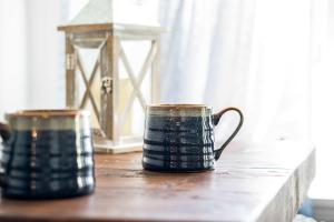 two coffee mugs sitting on a wooden table at The Hideaway at Hayloft Lodge - Chic & Unique Stay in Lake Geneva +16 photos