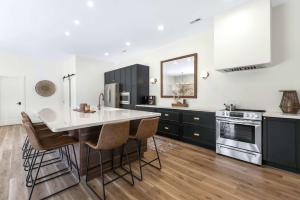 una cucina con armadi neri e un'isola cucina con sgabelli da bar di Bearcat Bungalows - Two Homes One Rental - Sleeps 22 a Sunrise Beach Altre 31 foto