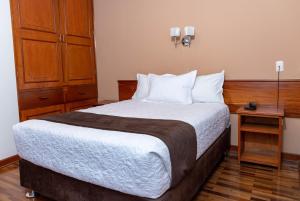 a bedroom with a large bed and a wooden cabinet at El Meson Hotel Tacna in Tacna +2 photos