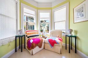 a living room with two chairs and two windows at Aldrich House - PG Charmer Walk to Lovers Point in Pacific Grove