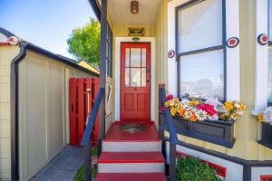 a red door on a house with flowers on the steps at Aldrich House - PG Charmer Walk to Lovers Point in Pacific Grove