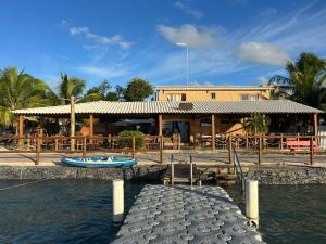 a restaurant with a dock next to a body of water at Pousada Algas Marinhas in Mangue Sêco