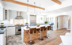 a kitchen with white cabinets and a island with bar stools at A True Vacation Masterpiece in Corona del Mar