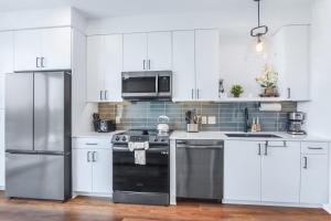a kitchen with white cabinets and a stainless steel refrigerator at Chic Condo Minutes to Downtown Gruene & More in New Braunfels