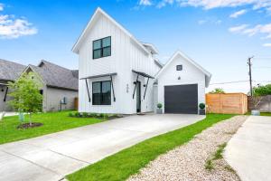 a white house with a garage and a driveway at Chic Modern Farm Haus - Minutes to Everything in New Braunfels