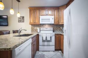 eine Küche mit Holzschränken und einem weißen Kühlschrank in der Unterkunft Waterwheel Hideaway - Cozy Condo for 6 with Resort-style Amenities in New Braunfels