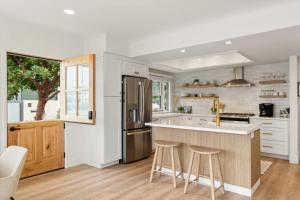 una cocina con armarios blancos y una isla con taburetes. en Bayside Getaway Waterfront, en Newport Beach 21 fotos más