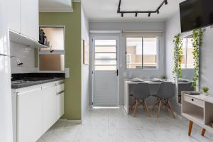 a kitchen with white cabinets and a table and chairs at Manacá Studio Praticidade e Estilo na Aclimação in Sao Paulo