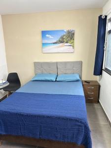 a bedroom with a blue bed and a beach at Suítes do Jajá 900m da Praia do Forte Centro de CF in Cabo Frio
