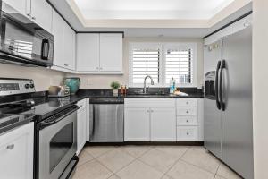 a kitchen with white cabinets and a stainless steel refrigerator at Spacious Beachfront Retreat - Sauna Pools & More in Perdido Key