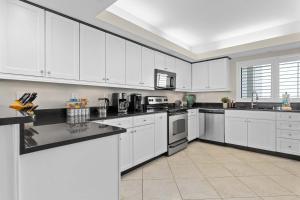 a white kitchen with white cabinets and appliances at Spacious Beachfront Retreat - Sauna Pools & More in Perdido Key +9 photos