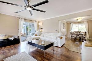 sala de estar con sofá blanco y ventilador de techo en O-side Oasis - Luxury Stay for 7, en Oceanside