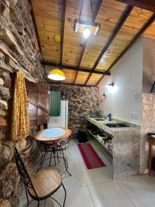 a kitchen with a table and a stone wall at Pousada Casa do Arco in Santana do Riacho