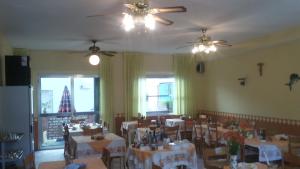 une salle à manger avec des tables, des chaises et des ventilateurs de plafond dans l'établissement Hotel Magda, à Rimini