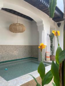 a swimming pool in a villa with yellow flowers at Riad Dar Balthazar in Marrakesh
