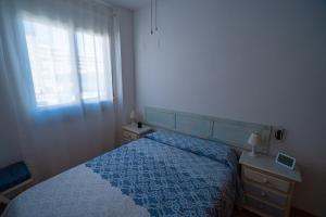 a bedroom with a blue bed and a window at Piso Playa de Canet in Canet de Berenguer +15 photos