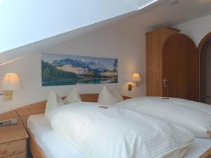 a bedroom with a large white bed with two lamps at 2-Raum FeWo Almenrausch - Hallenbad & Sauna in Fischen +10 photos