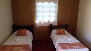 two beds in a room with a window at Recanto das Águas in Britânia +38 photos
