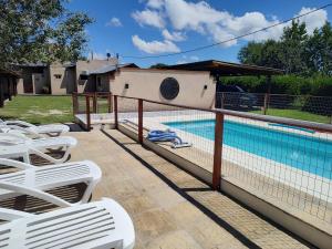 a swimming pool with white lounge chairs next to a fence at Cabañas Finca del molino in Panaholma