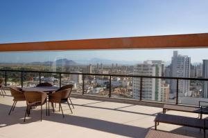 a balcony with a table and chairs and a view of a city at Promenade Soho Campos dos Goytacazes in Campos dos Goytacazes
