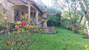 a garden with a fountain in front of a house at Eco Hotel Villa Canaan in Cobán