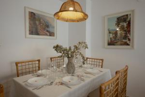 Una mesa de comedor con un mantel blanco y un jarrón con flores. en Comeback A un Suspiro del Mar, en La Herradura