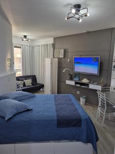 a bedroom with a blue bed and a flat screen tv at Loft Melhor do Sahy - Magaratiba RJ in Mangaratiba