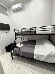 un letto a castello in una stanza bianca con una televisione di Masaniellohouse a Napoli