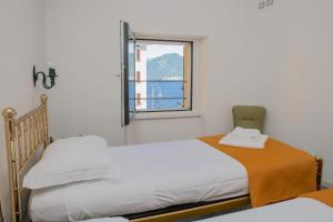 two beds in a room with a window at Casa Hygge Argegno Lago di Como in Argegno