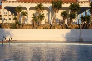 a pool with palm trees in front of a building at Utopia in Aljezur