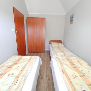 a room with two beds and a wooden cabinet at Apartamenty Afrodyta in Karwia +6 photos