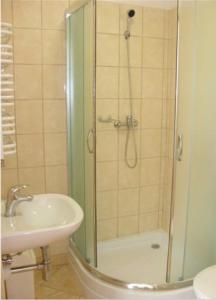 a shower with a glass door next to a sink and a toilet at Apartamenty Afrodyta in Karwia