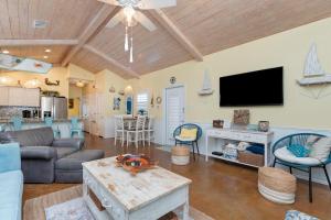 Una sala de estar con un sofá y un televisor. en Mango Bungalow - Sleeps 8 2 Community Pools, en Port Aransas