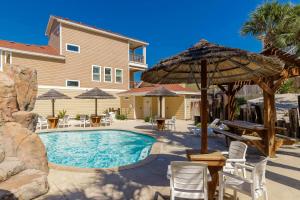 a pool with an umbrella and chairs and tables at Fun 4 Bedroom - Resort Pool Sleeps 12 in Port Aransas