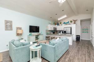 a living room with two blue couches and a kitchen at Fun 4 Bedroom - Resort Pool Sleeps 12 in Port Aransas
