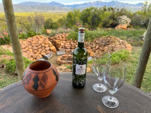 eine Flasche Wein und zwei Weingläser auf einem Tisch in der Unterkunft Renewal Retreat Klein Karoo Cottage in Uniondale